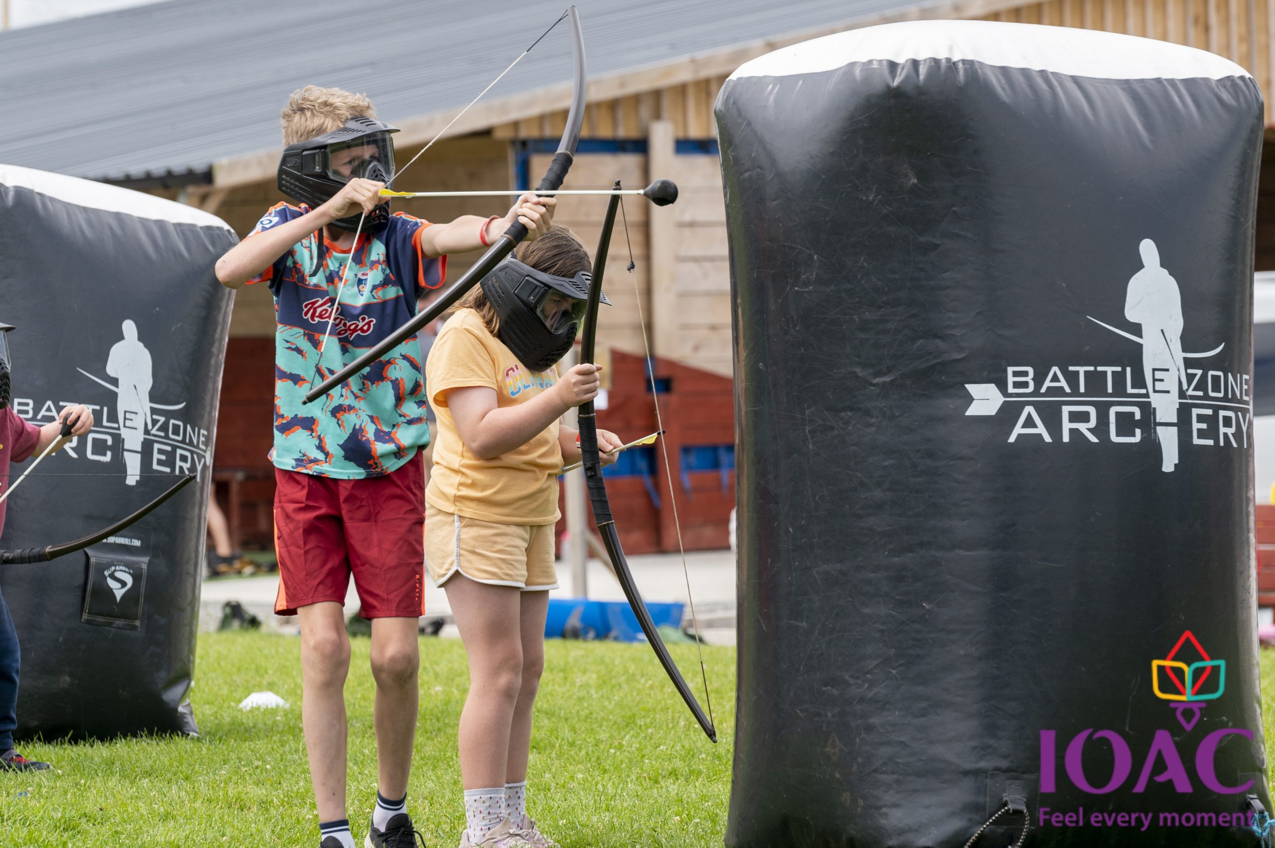 Children playing archery game with bows and masks outdoors.