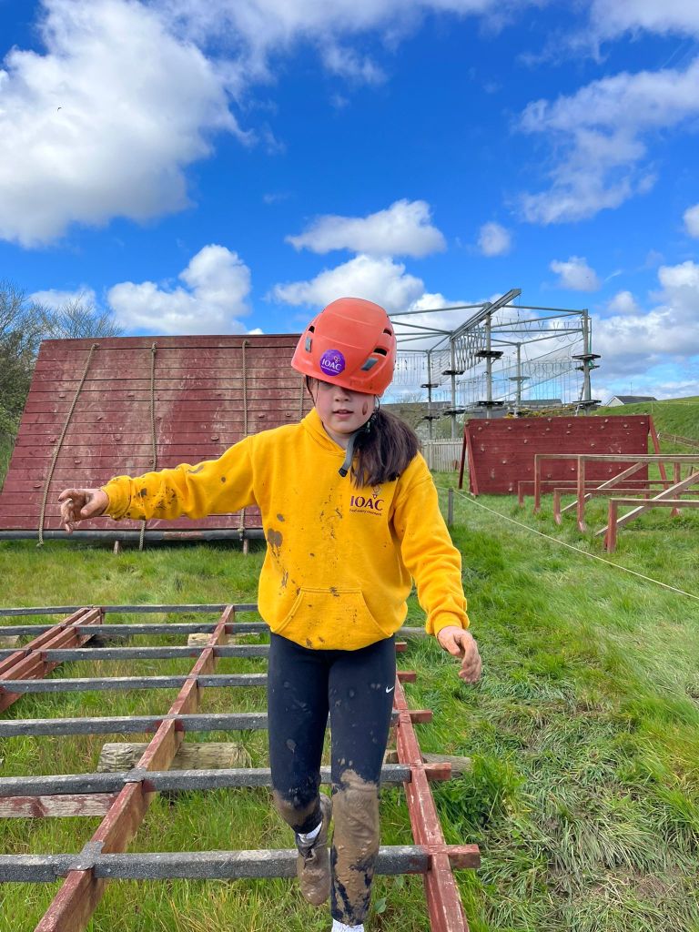 Person in helmet navigates outdoor obstacle course on metal bars.