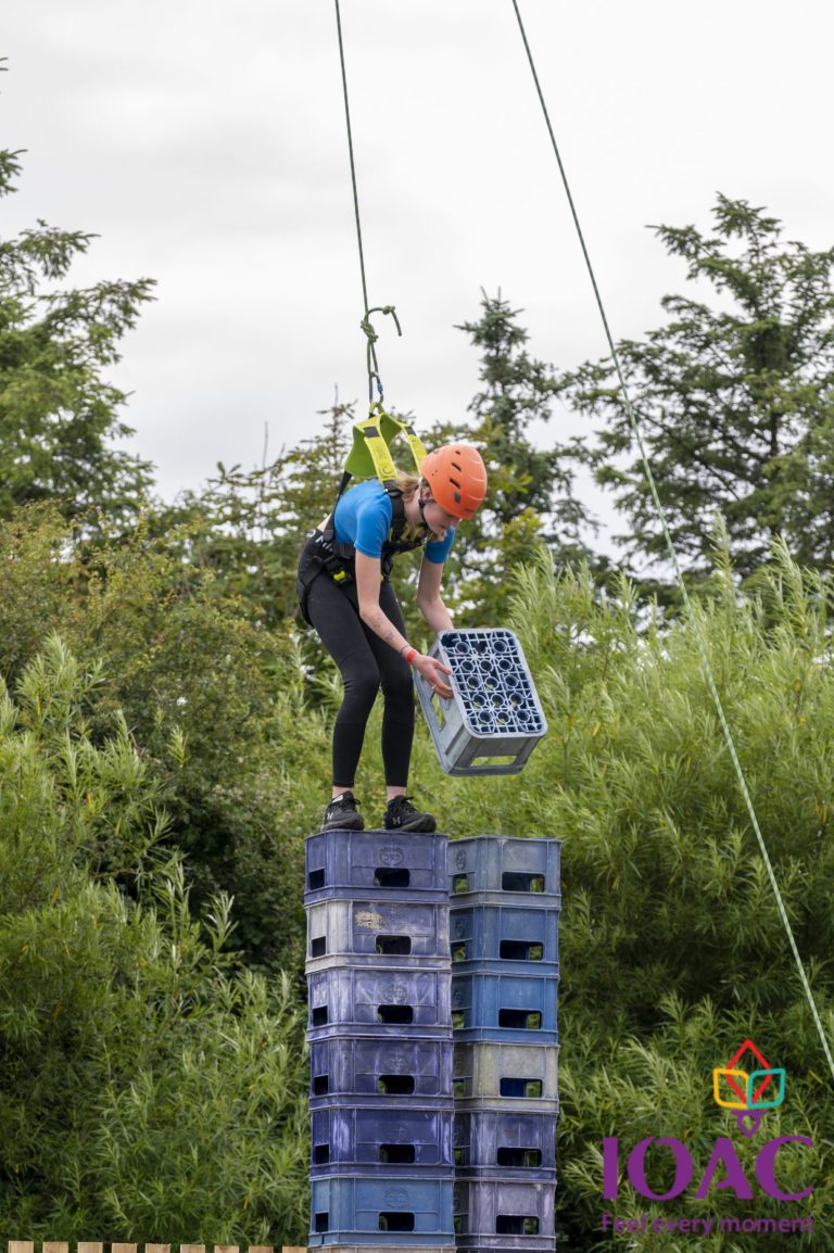 Person stacking crates while secured with a harness.