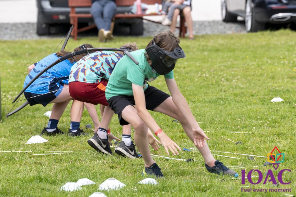 Kids balancing on a grass field wearing blindfolds during an outdoor activity.