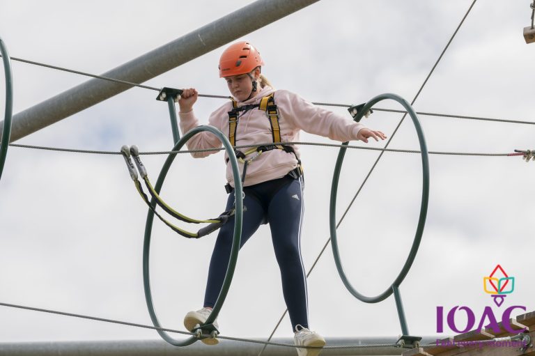 Person on high ropes course wearing helmet and harness.