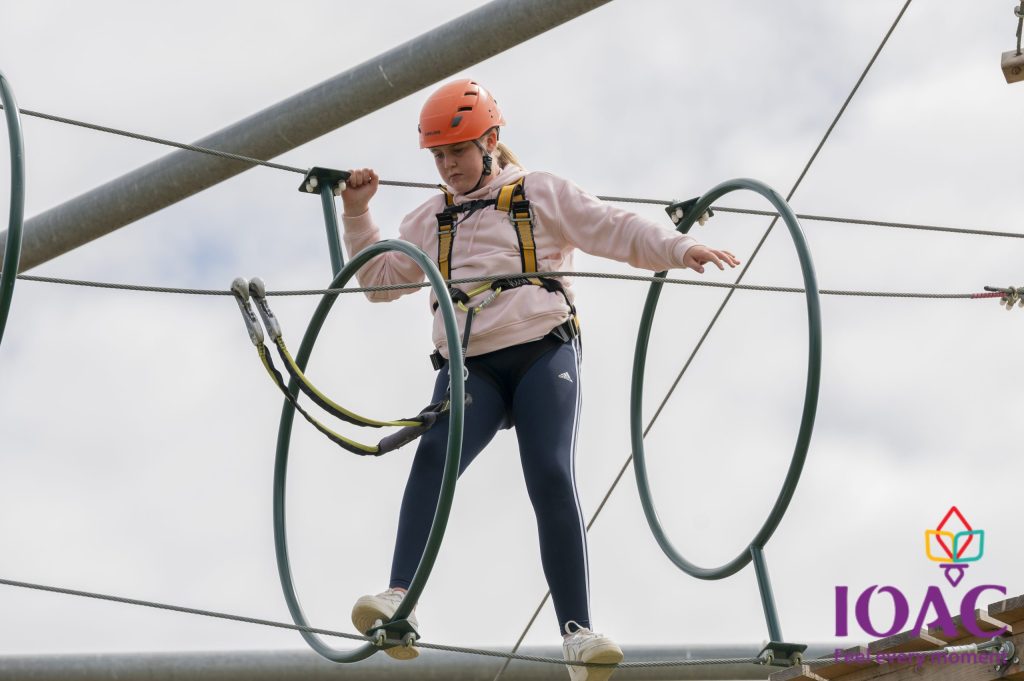 Person on high ropes course balancing inside circular hoops.