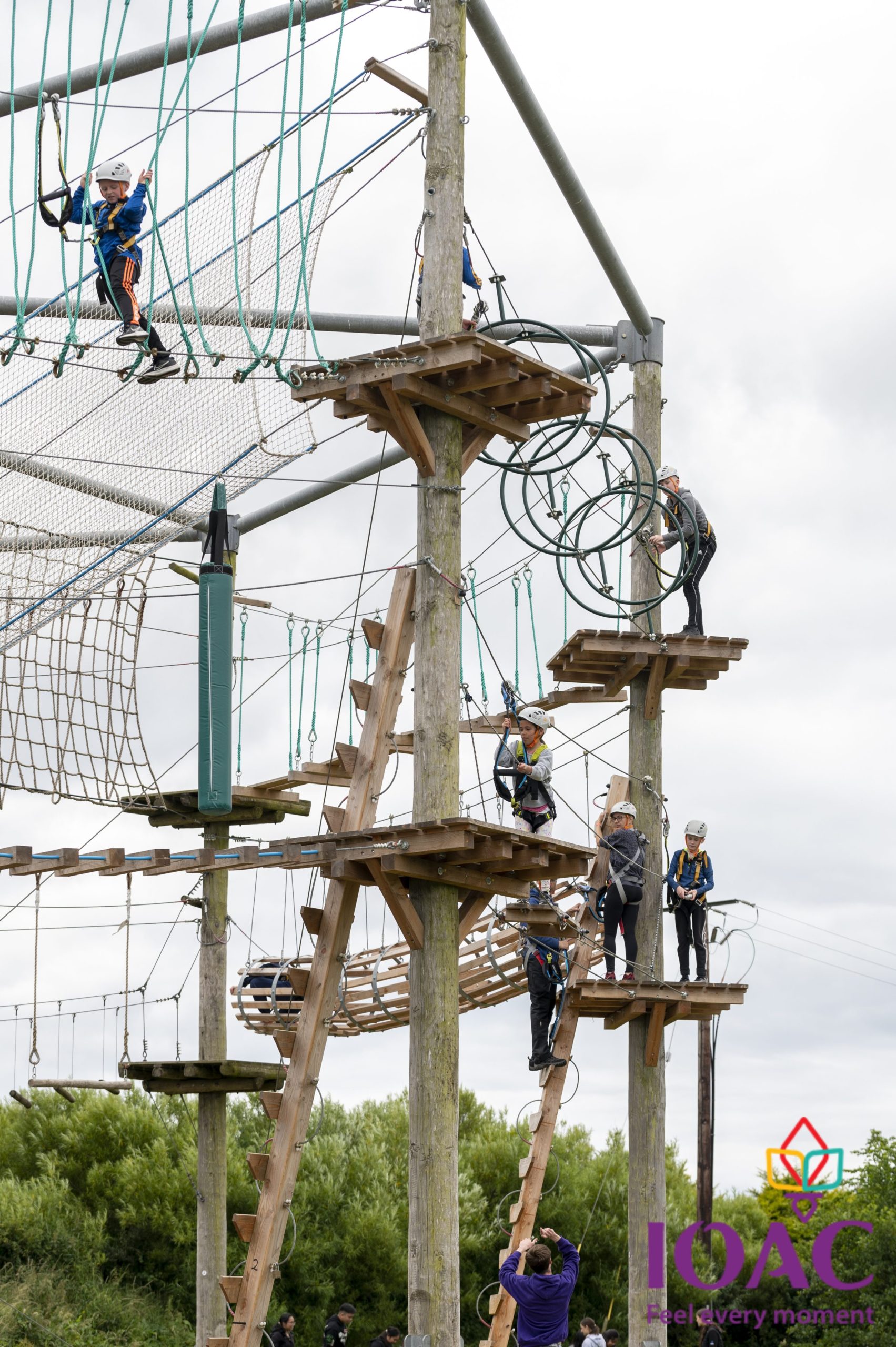 People engaged in a high ropes course with wooden platforms and nets.