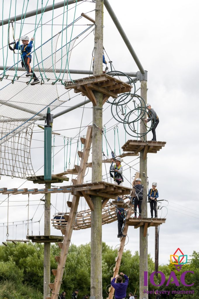 People engaged in a high ropes course with wooden platforms and nets.
