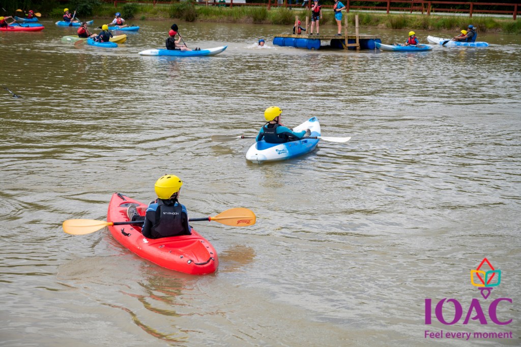 People kayaking on a lake wearing helmets and life vests.