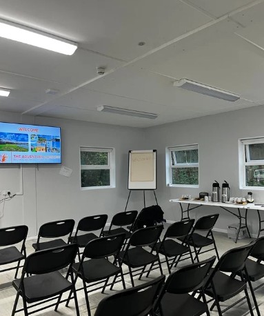 Empty conference room with chairs, screen, and refreshments table.