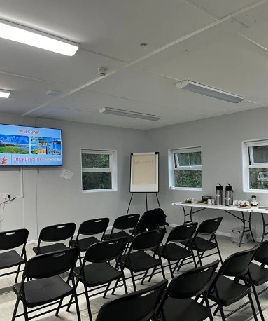 Empty conference room with chairs, screen, and refreshments table.