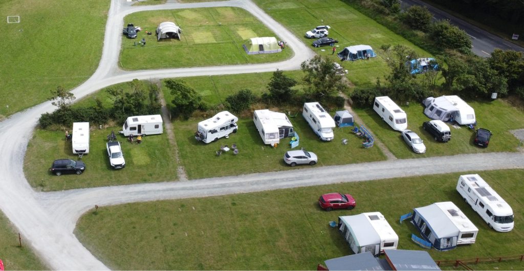 Aerial view of a campground with caravans and tents on grassy plots.