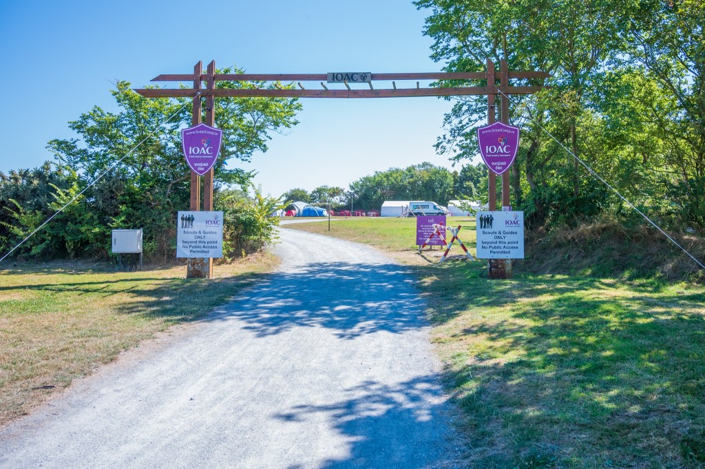 Wooden entrance gate to outdoor activity center with signs and path.