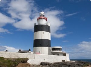 Tall black and white lighthouse against a cloudy sky.